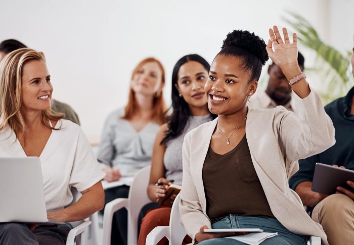 Shot of a young businesswoman raising her hand during a conference.